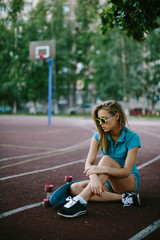 beautiful girl sitting near the skateboard