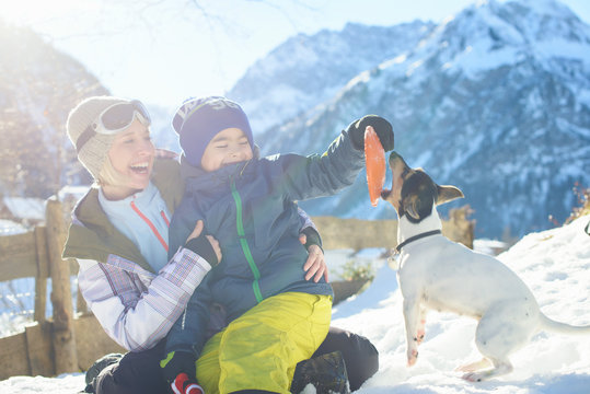 Happy family playing with a dog in a sun in Austrian Alps
