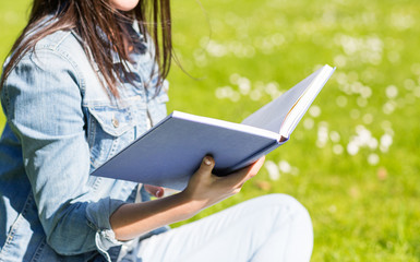 close up of smiling young girl with book in park