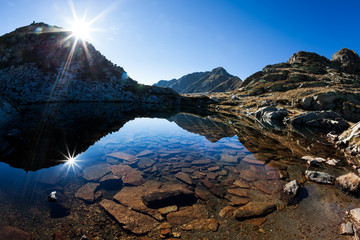 Small mountain lake in a sunny autumn day in italian Alps - obrazy, fototapety, plakaty
