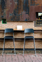 Fototapeta na wymiar Two cafe chairs against brick wall