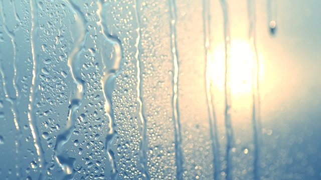 Flowing down water drops on glass. Selective focus. Sunset.