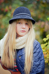 young  blonde teen girl playing guitar in the park