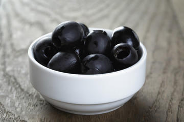 black olives from can in bowl on table