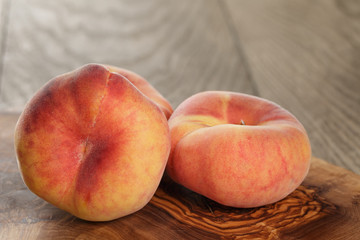 Fototapeta na wymiar ripe flat peaches on olive board