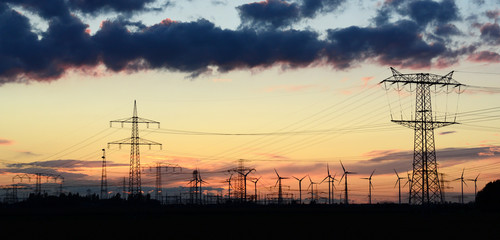 Windräder und Strommasten im Abendlicht