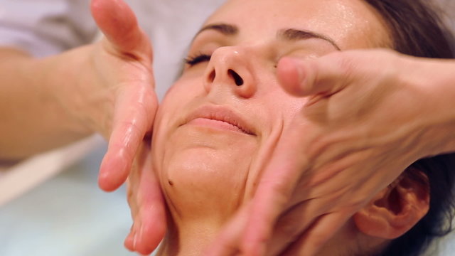 Beautician doing massage of female faces.