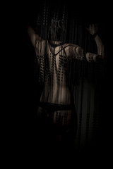 Fitness nude woman back through a curtain wire
