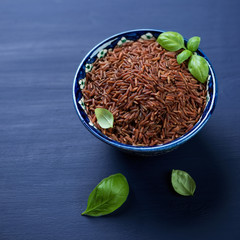Close-up of raw red kernel rice in a ceramic pialat, studio shot