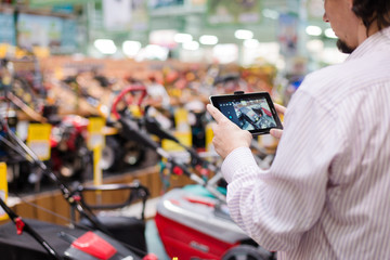 Man choosing lawnmowers in supermarket or DIY