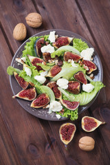 Salad with figs, mozzarella and walnuts, rustic wooden surface