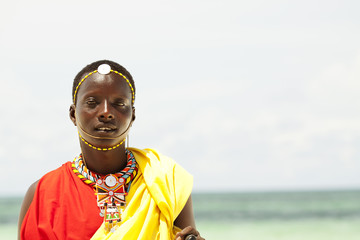 Young massai warrior man posing on bright sunny beach in Kenya - obrazy, fototapety, plakaty