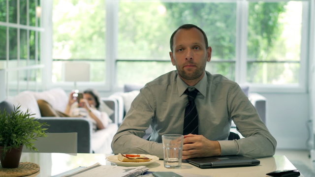 Gloomy businessman looking to the camera at home