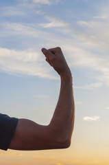 Man posing at sunset, sowing biceps. Nature background