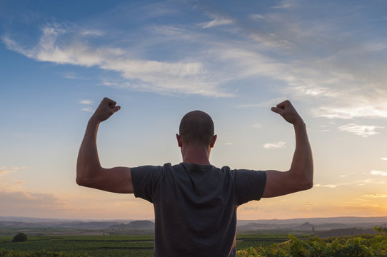 Man posing at sunset, sowing biceps. Nature background