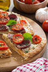 delicious pizza with salami and tomatoes on a wooden board