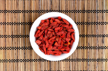 Goji berries in white bowl on oriental mat