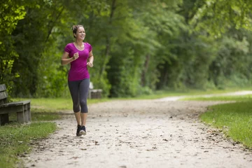 Tuinposter Fit young woman jogging in a park © Johannes Lehner