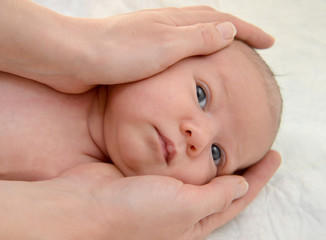 Mother's hands embrace the head of the baby