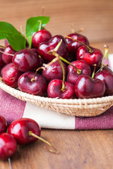 Many fresh cherries in bamboo basket