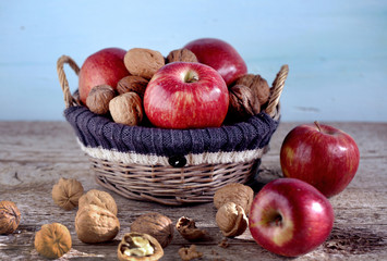 Basket full of red apples and walnuts in shells, autumn scene