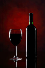 Red wine glass with bottle on the red background