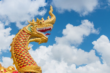 Fototapeta na wymiar The golden great naga statue in white cloud blue sky background