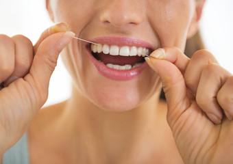 Fototapeta premium Closeup on young woman using dental floss