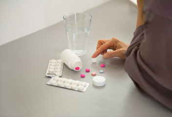 Closeup on young woman choosing pills