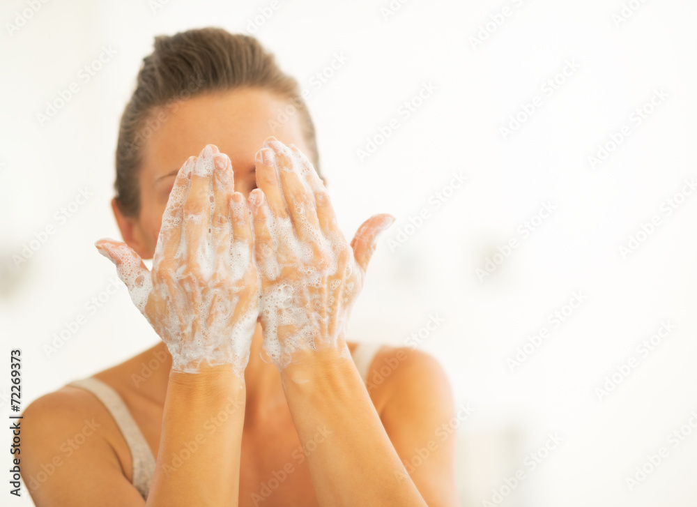 Wall mural young woman washing face in bathroom