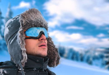 Fototapeta na wymiar Portrait of a man wearing an ear flap hat and ski glasses