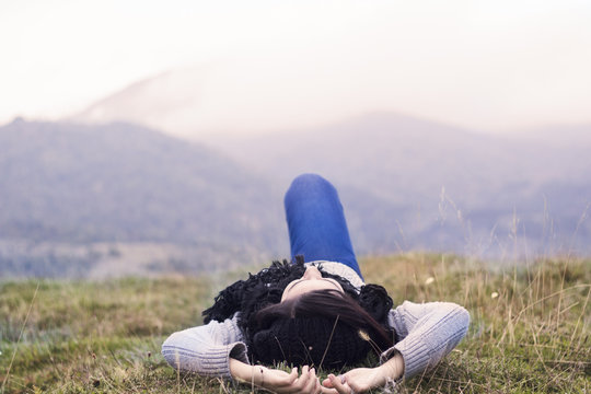 Young woman lying on the grass with Mountain view