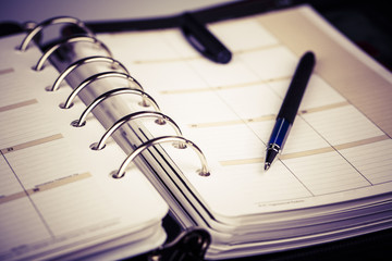 Personal organizer or planner with pen on white background