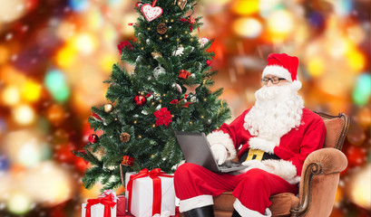 man in costume of santa claus with laptop