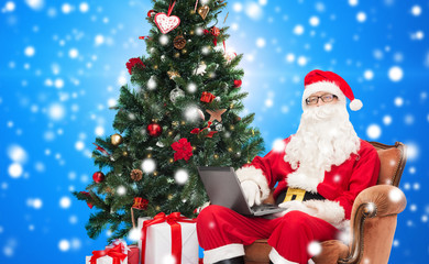 man in costume of santa claus with laptop