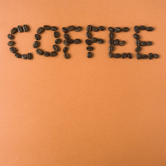 coffee spelled out with roasted coffee beans, on orange backgrou