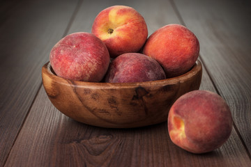 wooden bowl with some peaches on the table