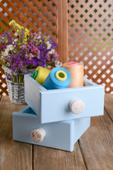 Sewing Accessories in wooden boxes on table on brown background