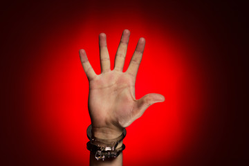 hand in handcuffs over red background