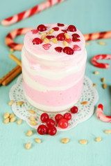 Cranberry milk dessert in glass jar, on color wooden background