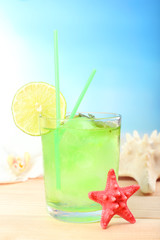 Refreshing cocktail on wooden table on blue background