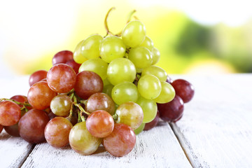 Bunches of ripe grapes on wooden table on natural background
