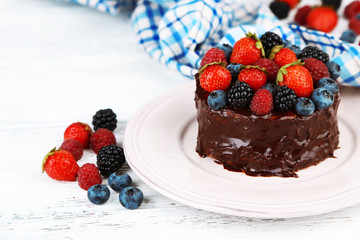 Tasty chocolate cake with different berries, on wooden table