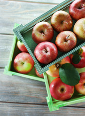 Juicy apples in boxes on wooden background