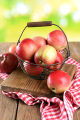 Sweet apples in wicker basket on table on bright background