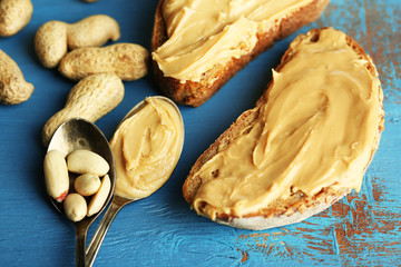 Tasty sandwiches with fresh peanut butter on wooden background