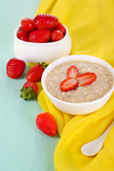 Tasty oatmeal with strawberry on table close-up
