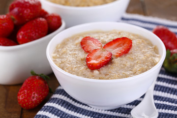 Tasty oatmeal with strawberry on table close-up