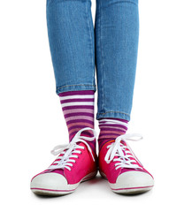 Female legs in colorful socks and sneakers isolated on white