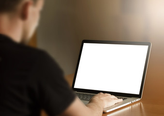 Man working on laptop with blank screen at home desk – rear view, remote work concept